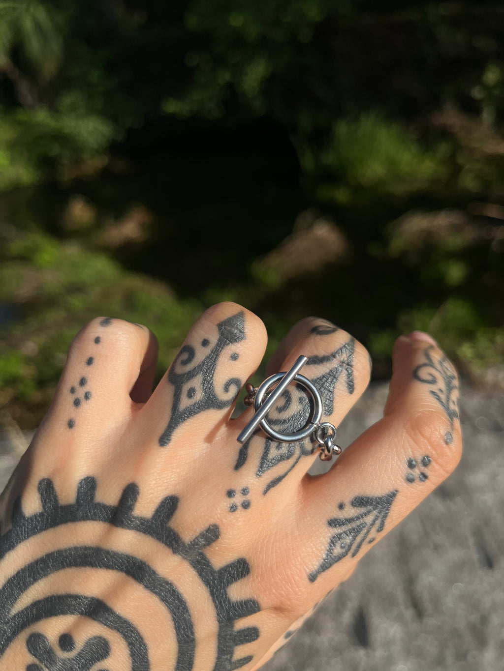 Silver industrial toggle ring worn on finger